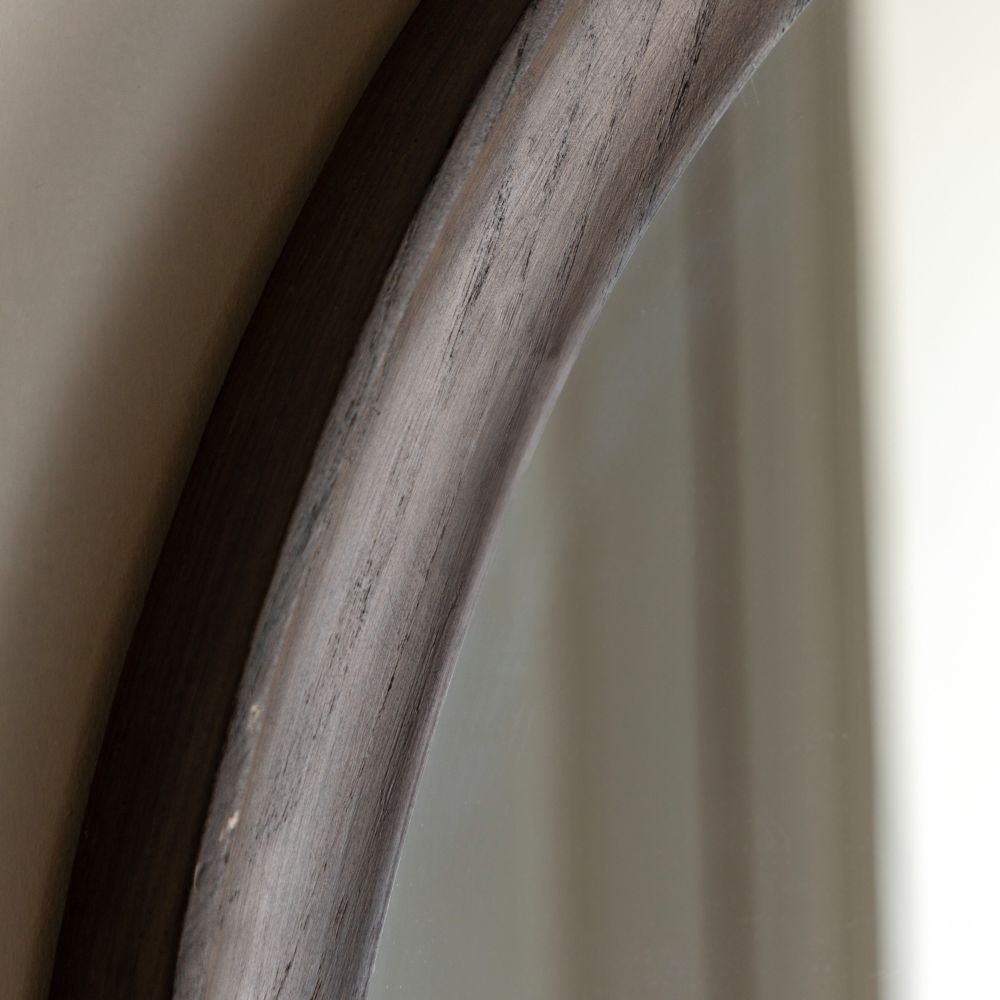 Angled close-up of a handcrafted dark wood mirror frame showing natural grain texture and curved organic edges.
