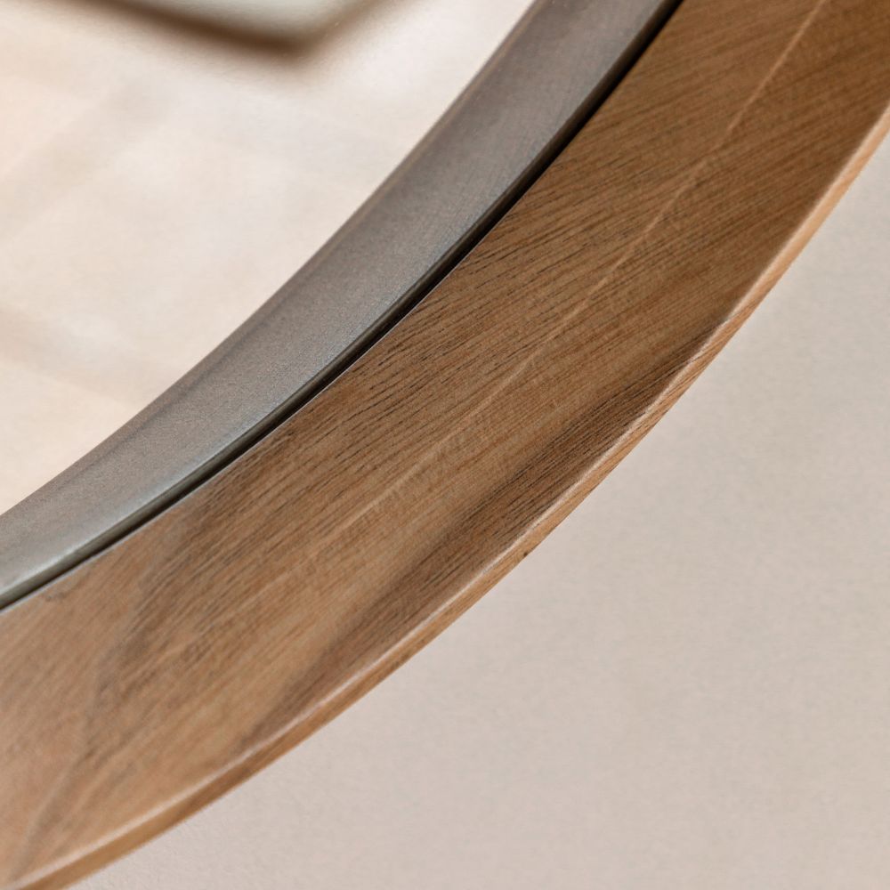Detailed close-up of a handcrafted natural oak wooden frame on a contemporary round wall mirror.