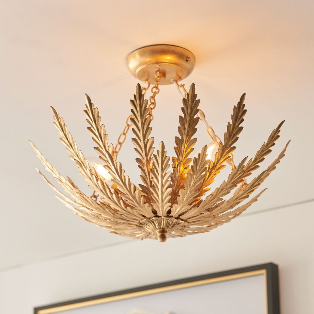 Antique gold ceiling light with layered leaf shaped metal fronds and warm glowing bulbs mounted on a ceiling.