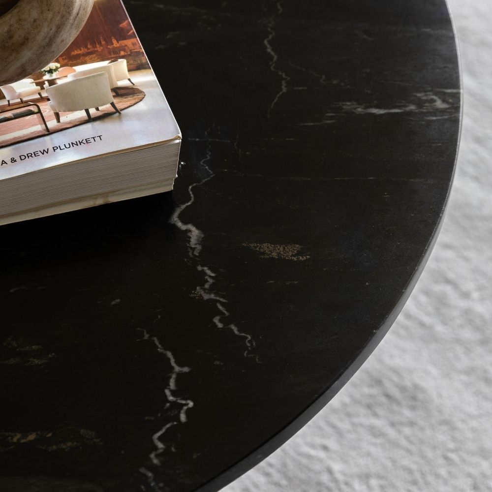 Detailed view of polished edge on black marble round coffee table with subtle veining and smooth finish.