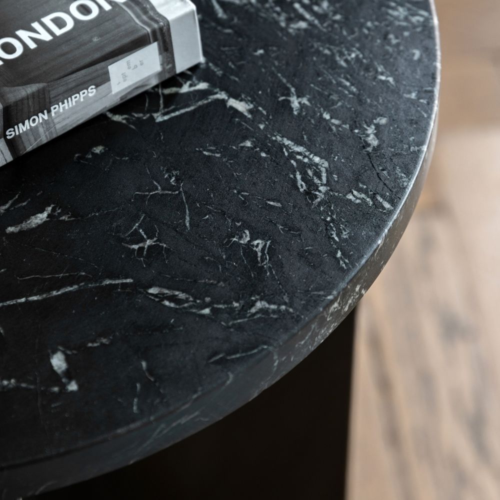 Close up of black marble side table showing detailed natural veining and smooth polished stone surface.
