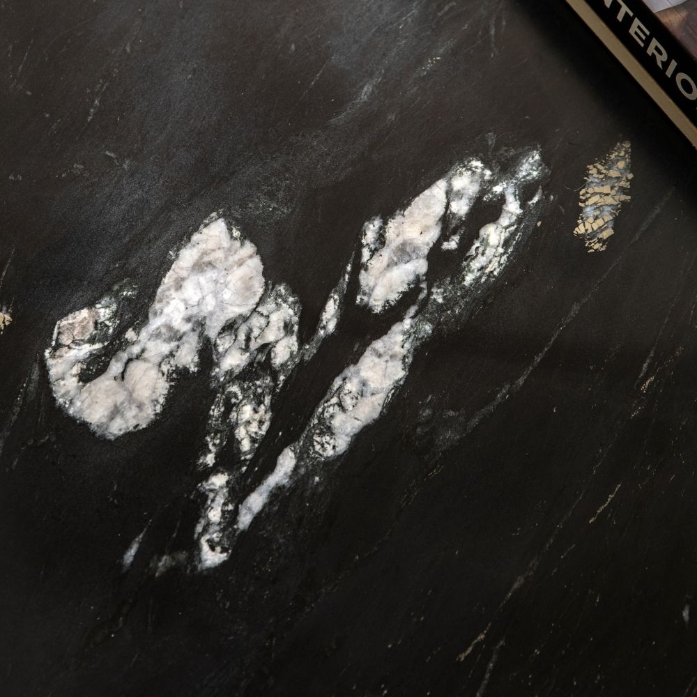 Close up of black marble surface showing natural white veining and unique stone texture.