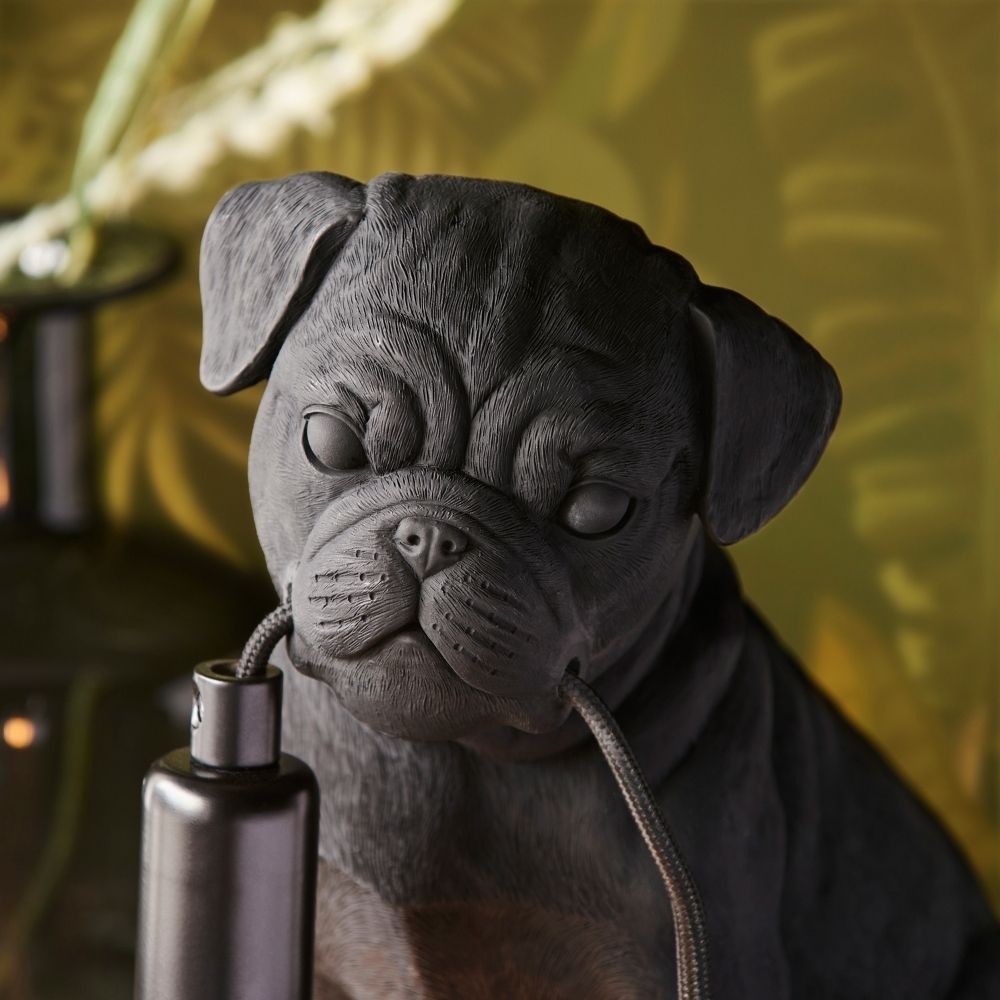 Close-up of black pug resin lamp face showing detailed texture and cable held in mouth, emphasising realistic sculpted design and craftsmanship.