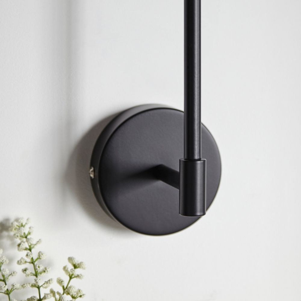 Detailed view of black wall light mounting plate and metal arm fixed to wall with smooth matte finish.