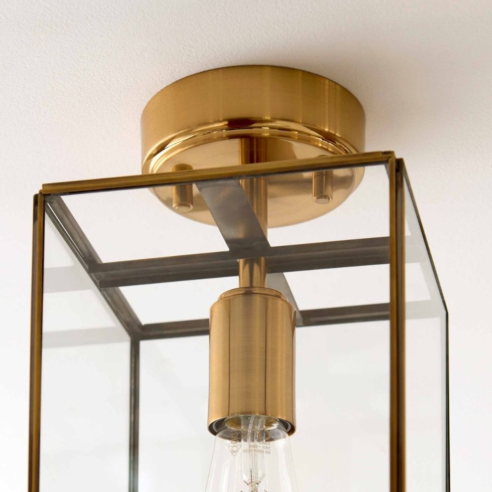 Close-up of brass frame corner on a glass ceiling light showing clean lines and reflective metal finish.