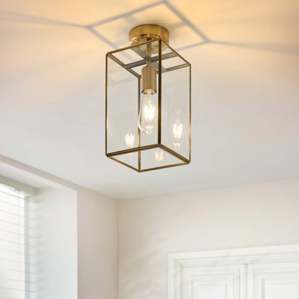 Brass and glass ceiling light installed in a bright interior space, casting warm light across the ceiling.