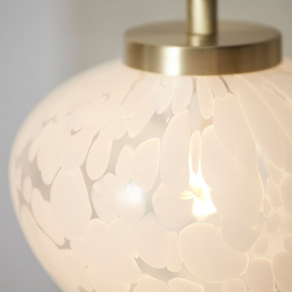 Close-up of brass and glass table lamp shade showing intricate textured glass pattern and warm diffused light effect.