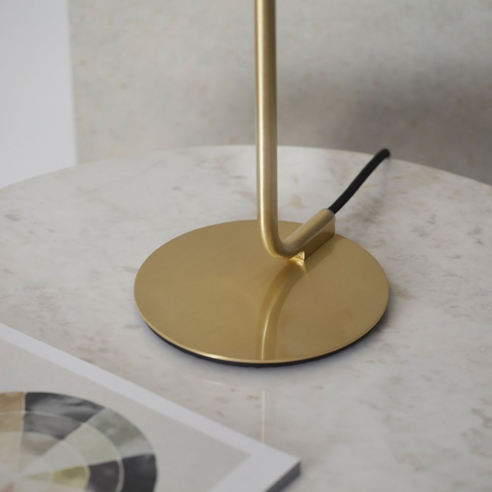 Close-up of brass table lamp base with smooth metallic finish and cable connection, placed on marble surface highlighting sturdy construction.