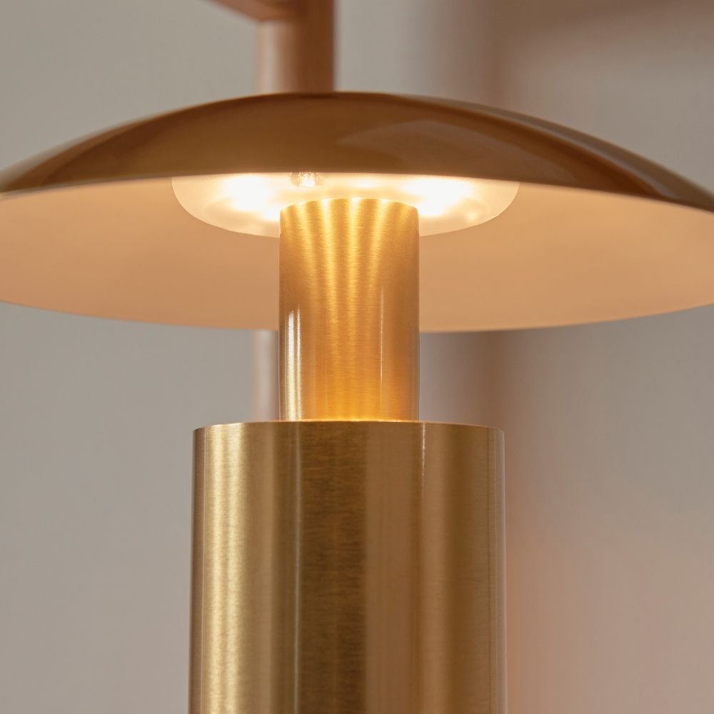 Close-up of brass mushroom table lamp showing warm LED glow beneath curved shade and brushed metal finish.