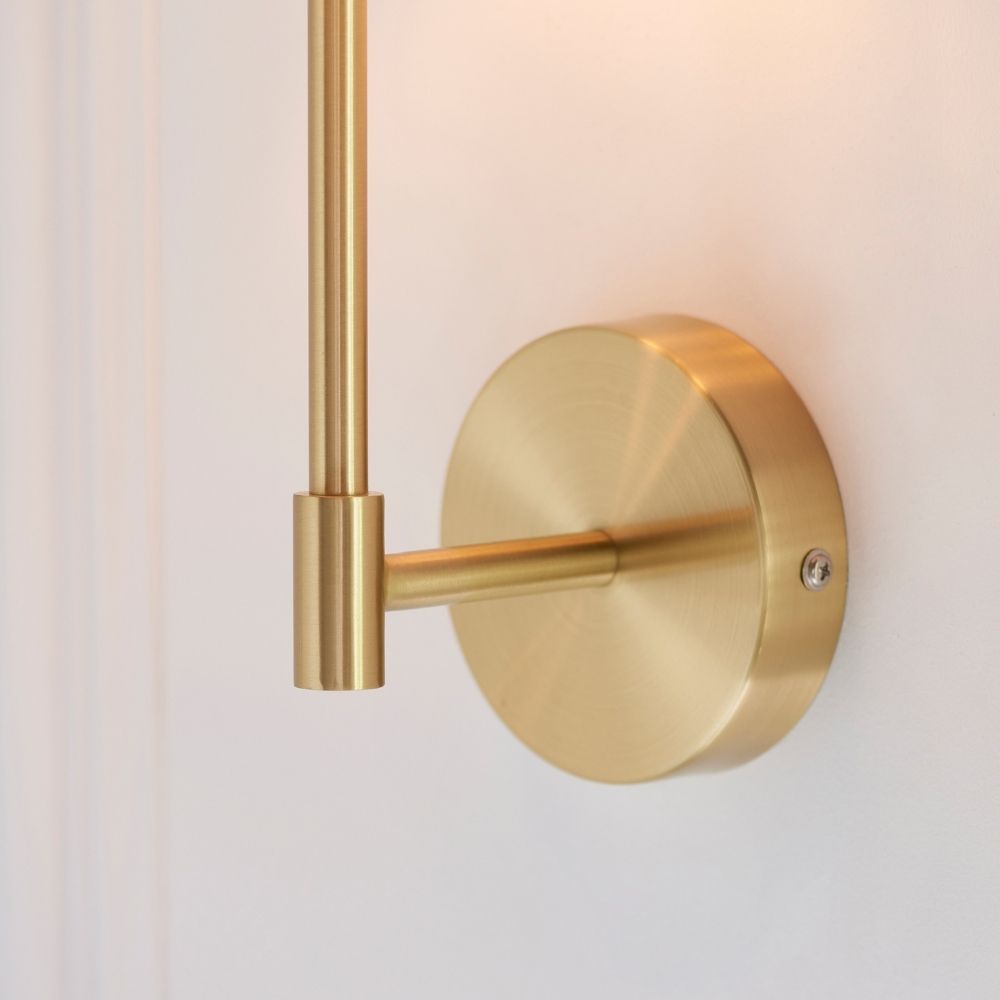Close up of white fabric lampshade on brass wall light showing soft glow and textured material.