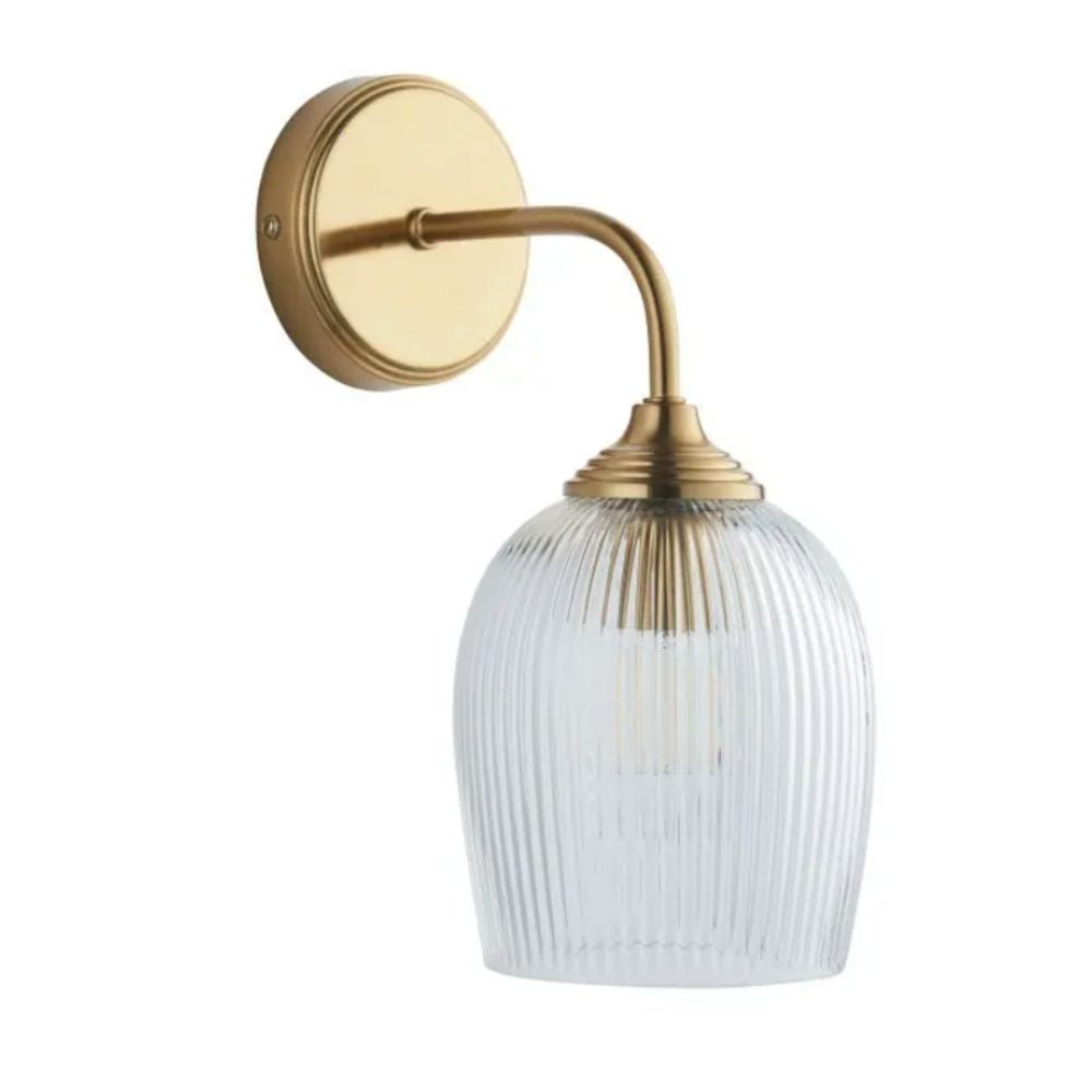 Wall-mounted brass sconce featuring a curved arm and ribbed glass shade, isolated on a white background.