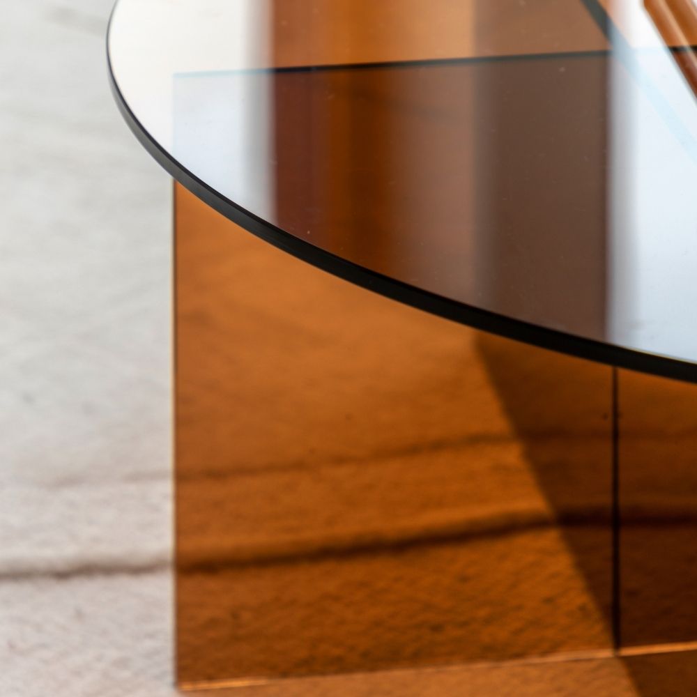 Close up of bronze tinted glass coffee table edge showing smooth finish and transparent layered design.