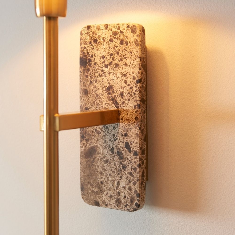 Detailed view of brown marble wall light backplate with natural stone texture and attached brushed brass arm.