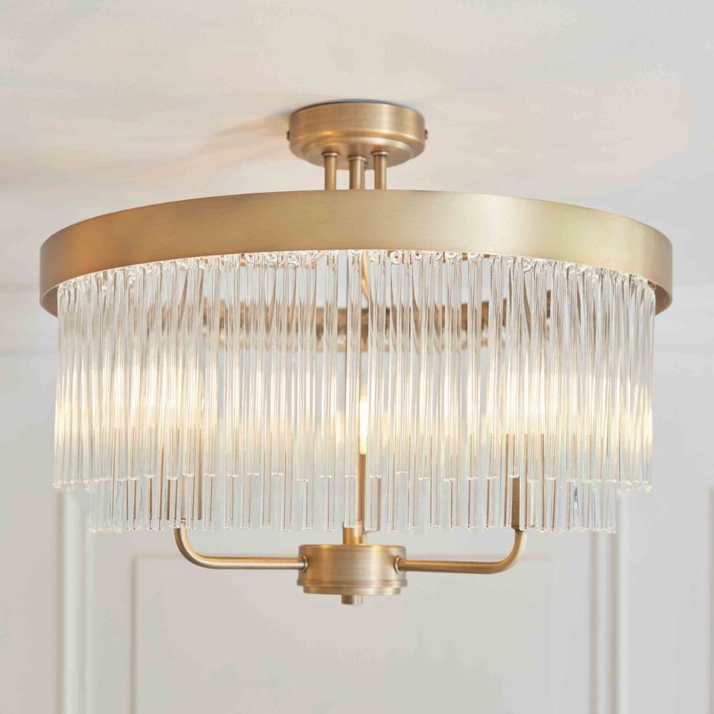 Brushed brass semi flush ceiling light featuring layered glass rods creating a soft ambient glow in a modern interior.