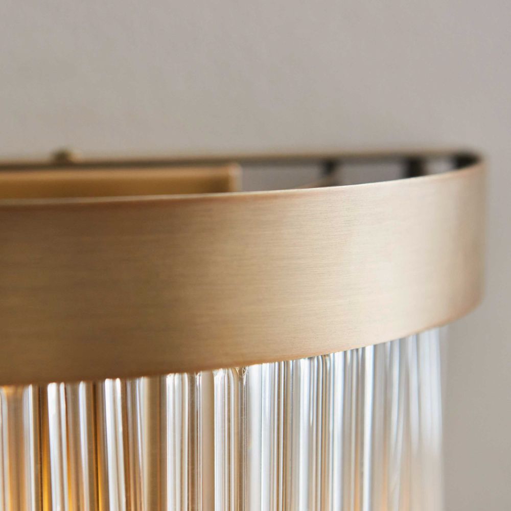 Detailed view of a brushed brass wall light frame with decorative hanging glass rods.