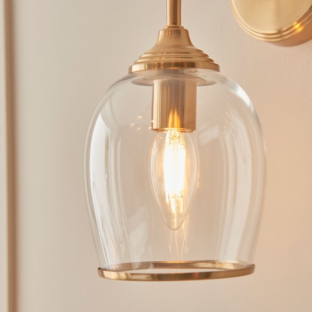 Detailed view of clear domed glass wall light shade with exposed filament bulb, creating a warm decorative lighting effect.