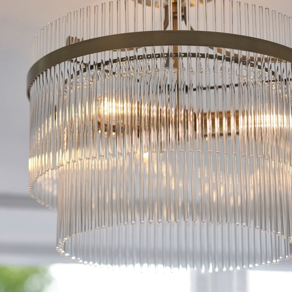 Close up of antique brass ceiling light showing detailed arrangement of clear glass rods and warm glowing bulbs.