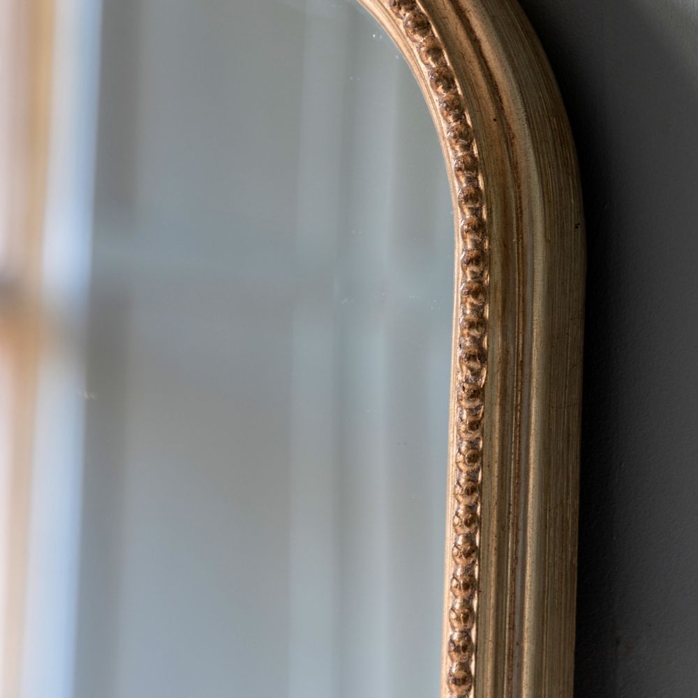 Close-up detail of an antique gold mirror frame with decorative beaded edging and vintage inspired finish.