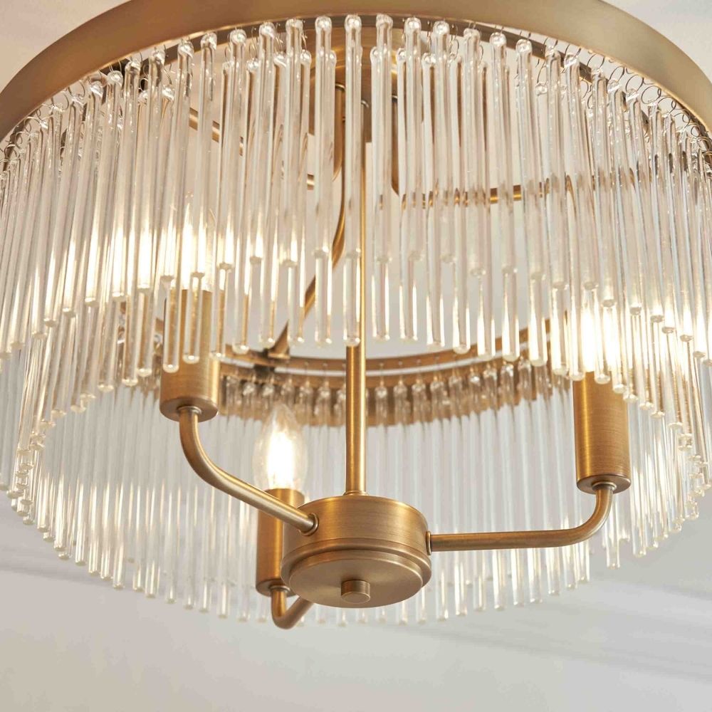 Detailed close up of a brass ceiling light fixture with vertically arranged glass rods and exposed bulbs.