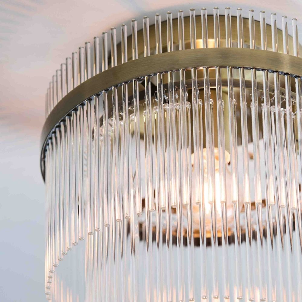 Close up of brushed brass frame with hanging vertical glass rods on a decorative flush ceiling light fitting.