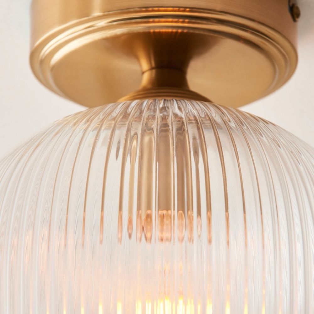 Detailed close up of brass ceiling mount and ribbed glass shade showing texture and warm light diffusion.