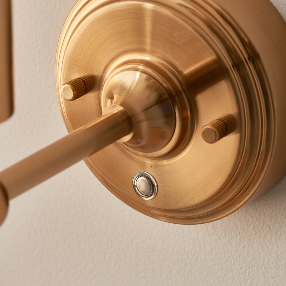 Close-up detail of a brushed brass wall light base with integrated dimmer switch and premium finish.