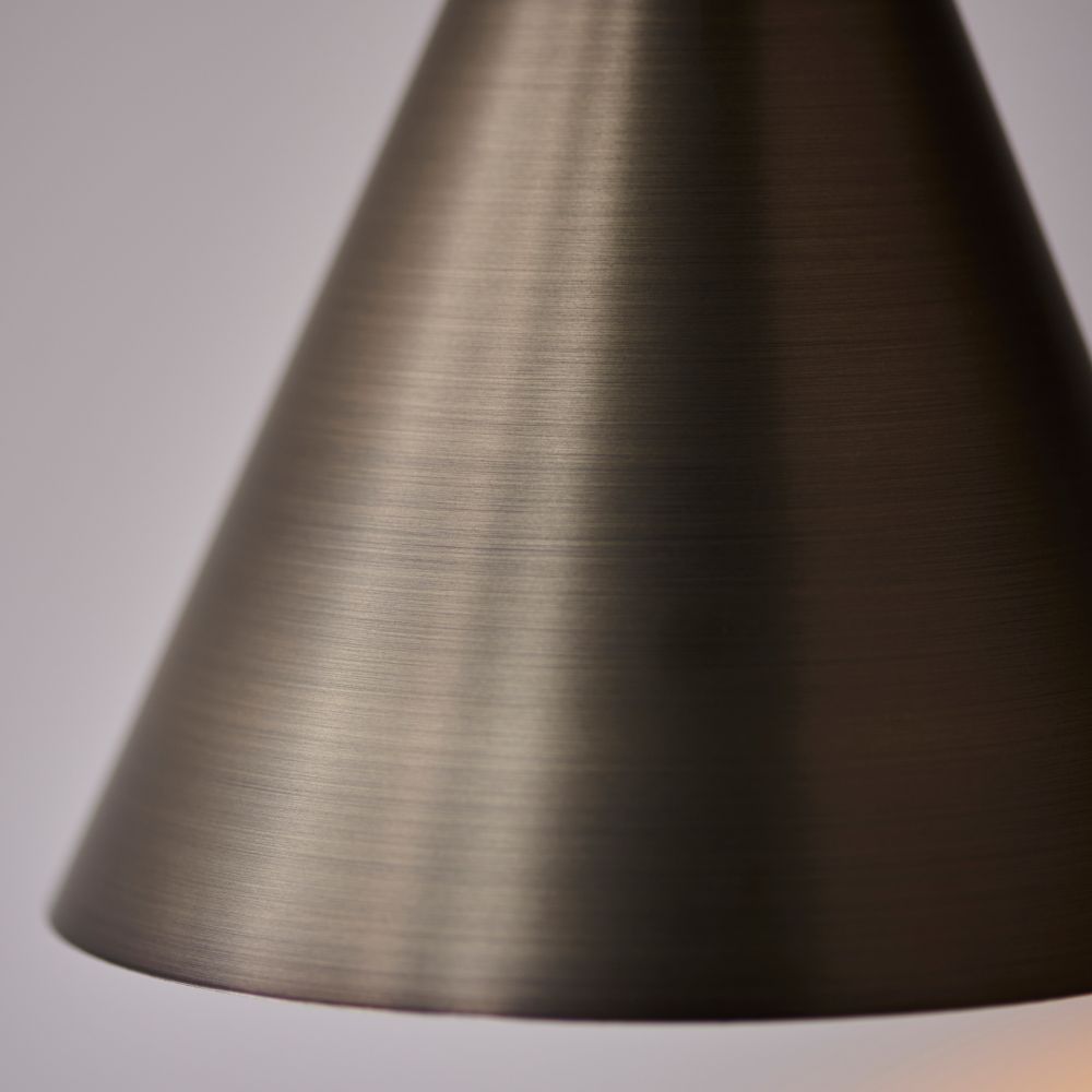 Close-up detail of a brushed bronze cone light shade with a smooth metallic finish.
