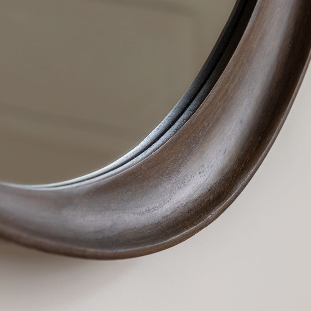 Close-up detail of a dark stained wooden frame on an organic shaped wall mirror with a smooth curved finish.