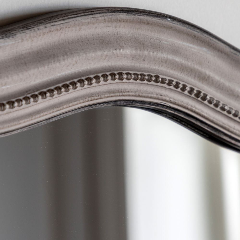 Close-up of a distressed grey mirror frame featuring curved edges and decorative beaded trim detail.