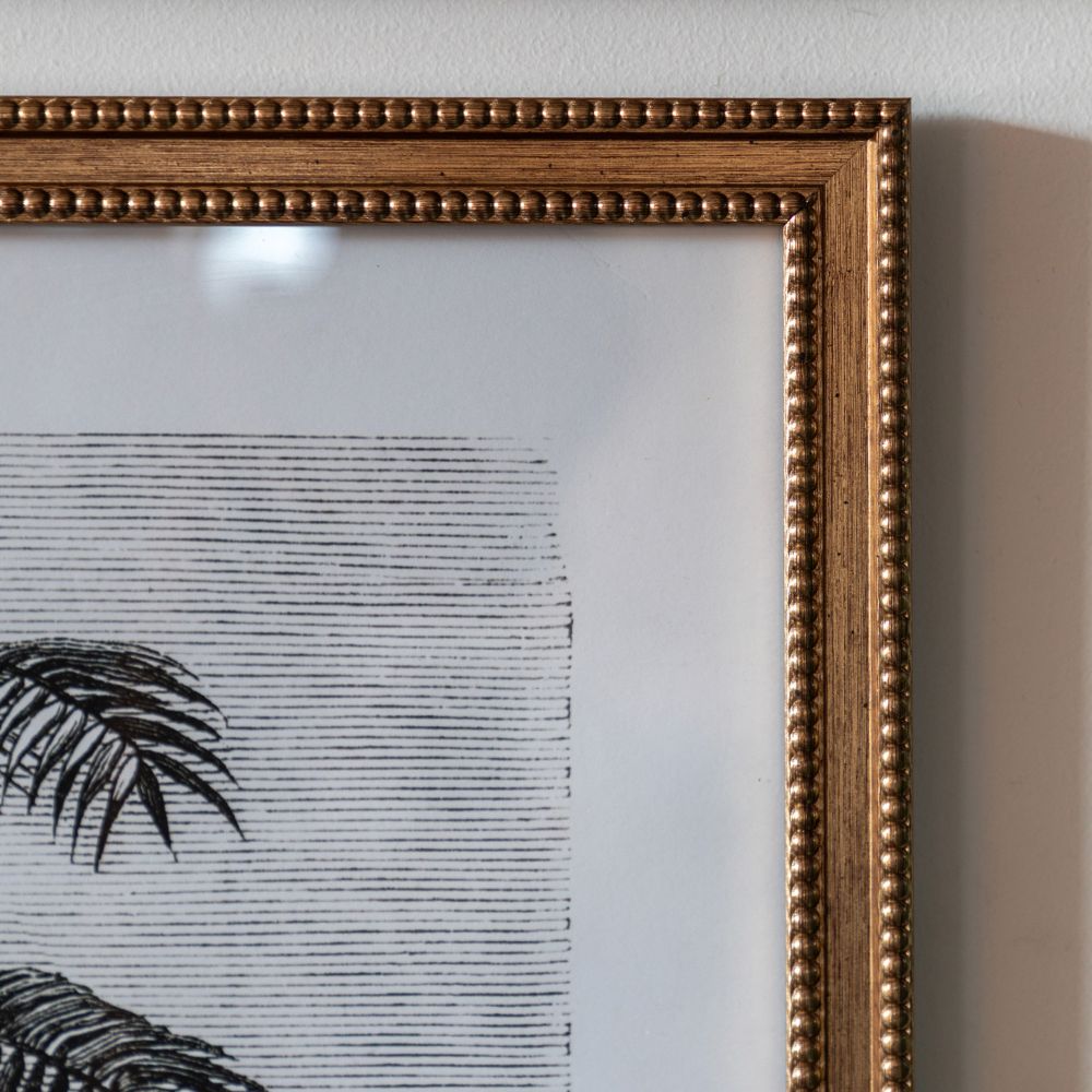 Close-up detail of an antique-style gold beaded frame surrounding a monochrome botanical palm tree print.