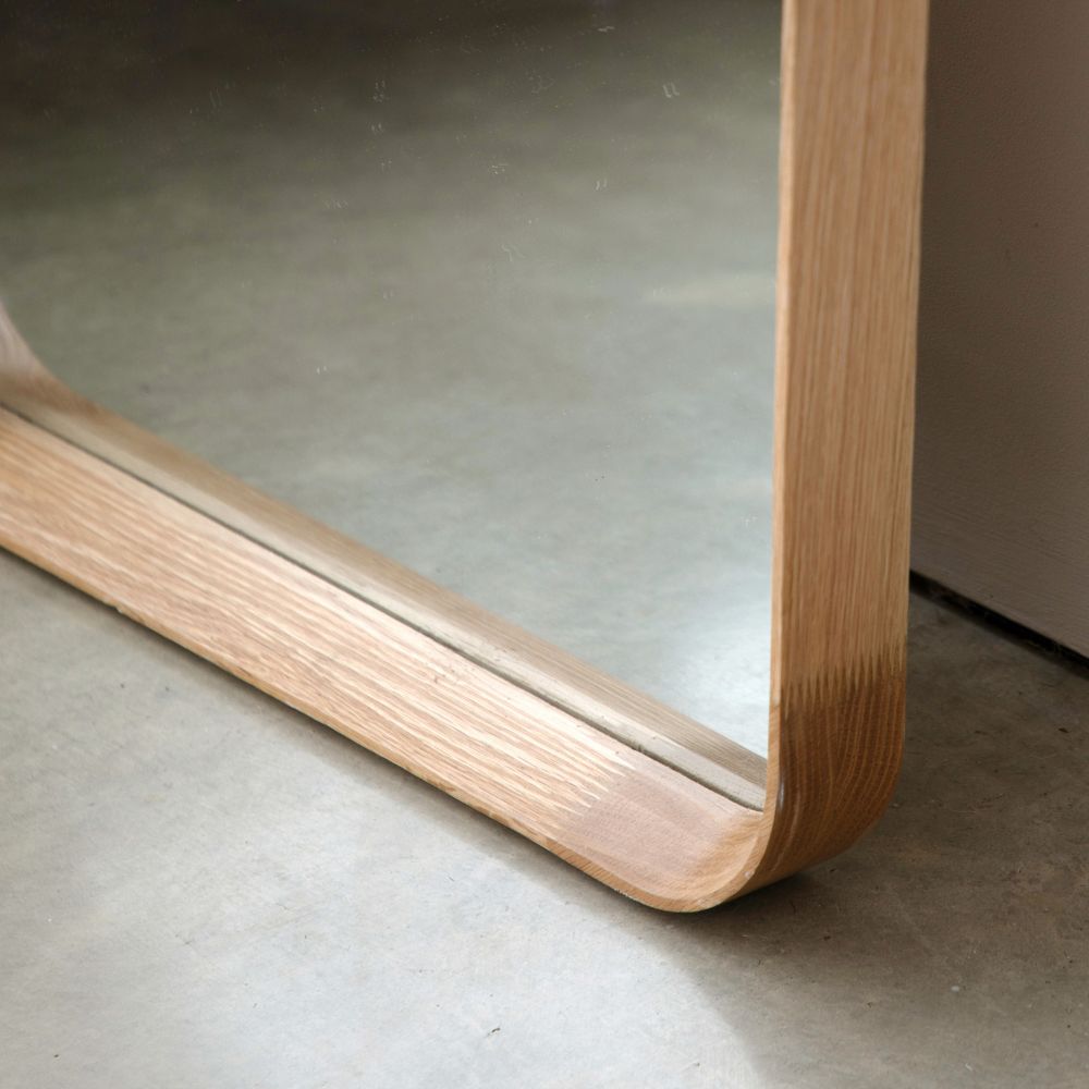 Close-up detail of a natural oak arched mirror frame showing smooth curved corners and visible wood grain texture.
