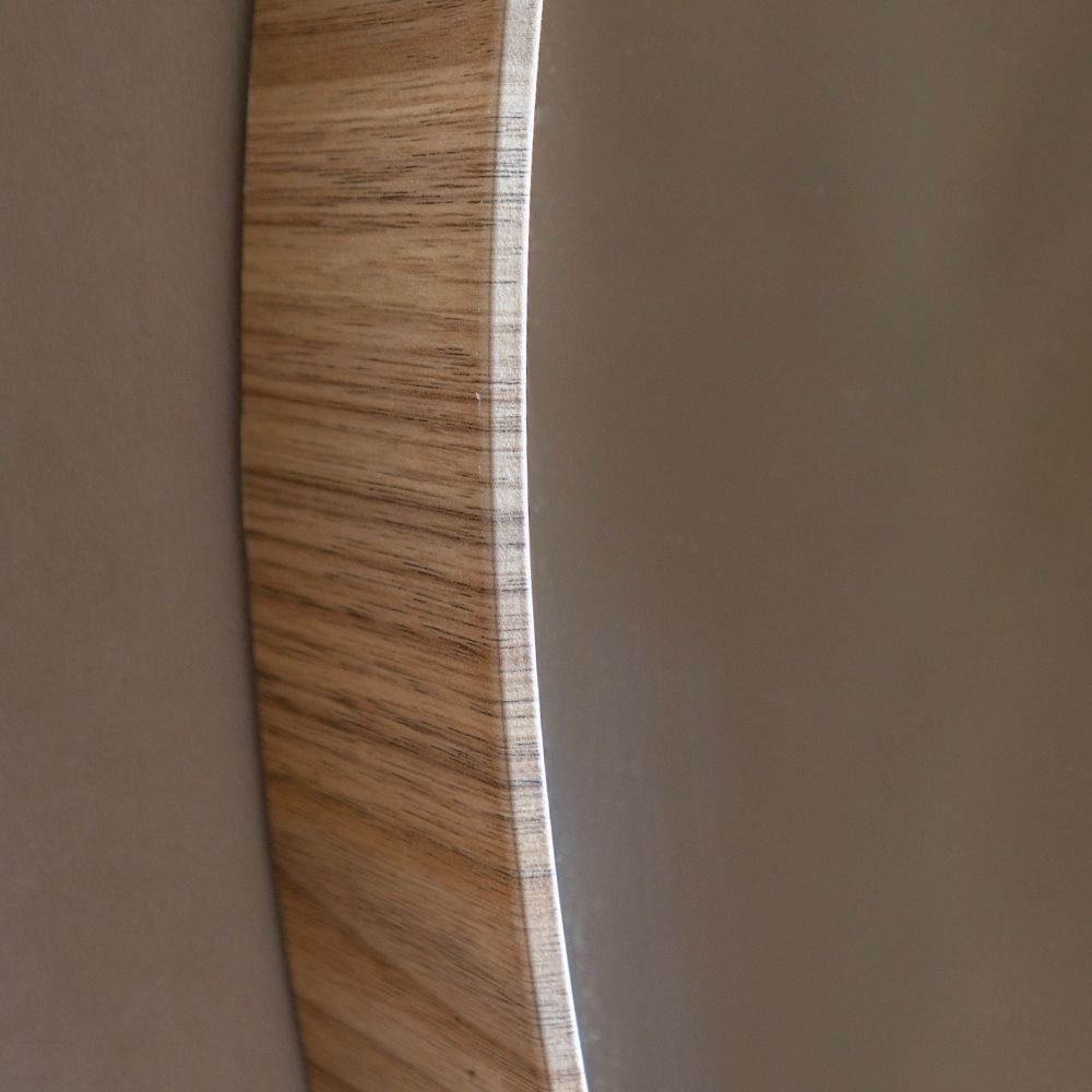 Angled close-up detail of a solid oak frame and glass edge on a modern round wall mirror.