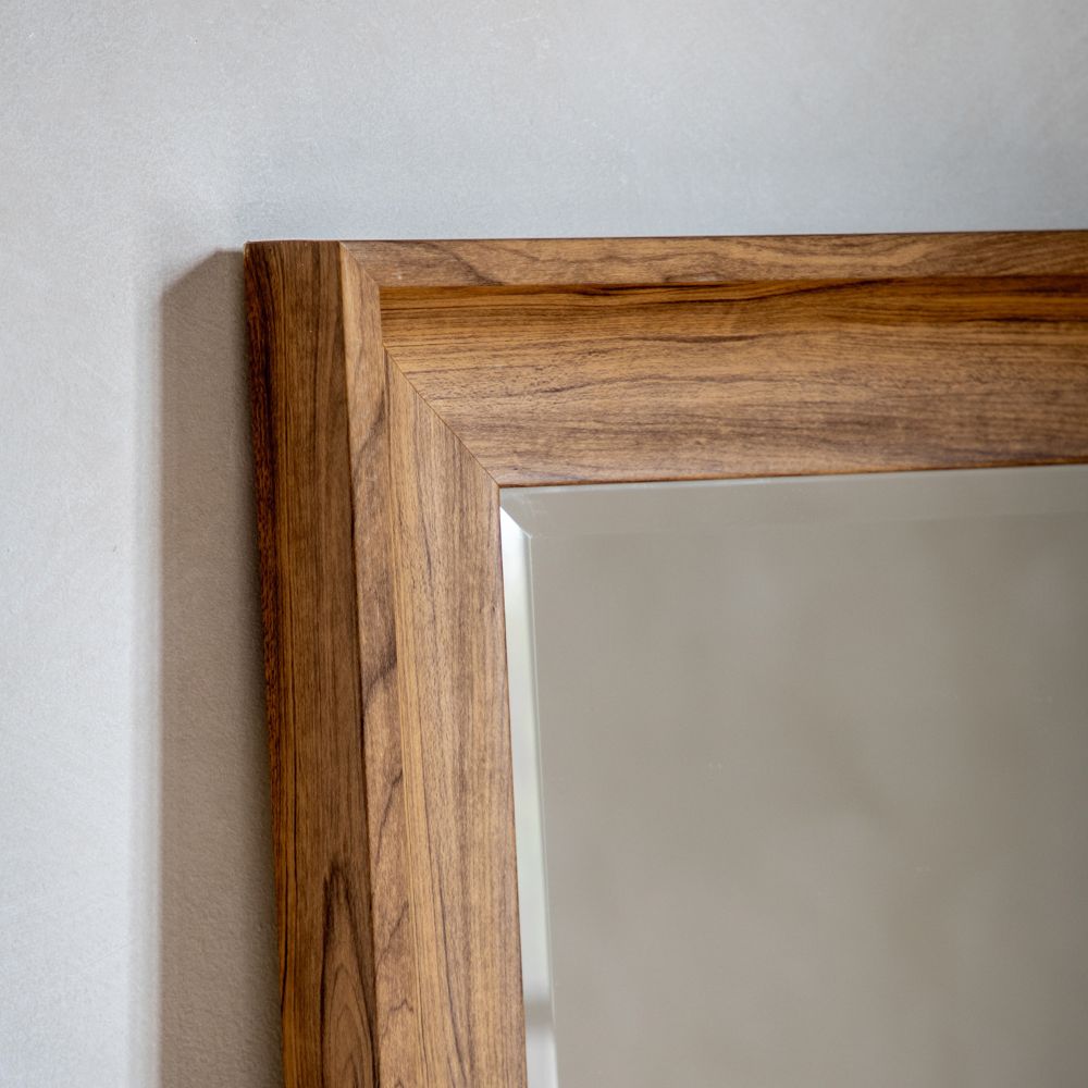 Close-up detail of a rectangular mirror with a natural wood frame showing warm grain texture and clean angled edges.