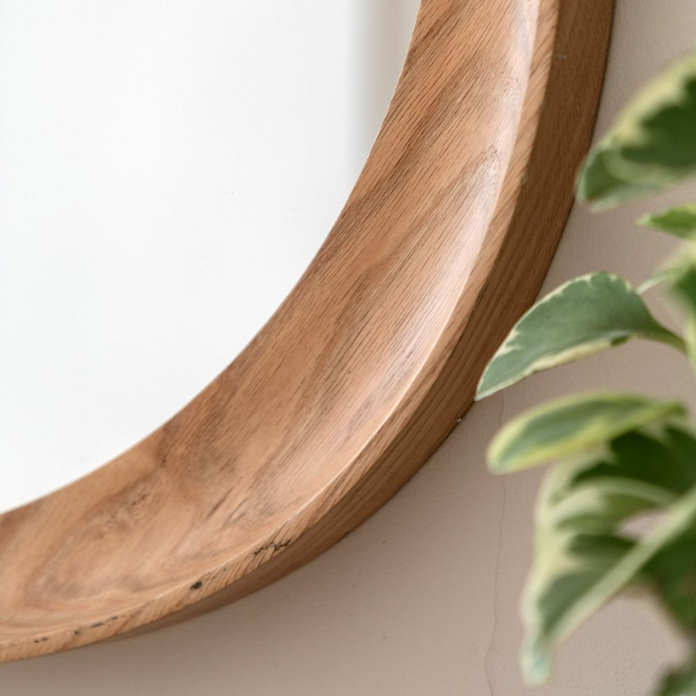 Close-up detail of a handcrafted organic oak wooden frame on a contemporary wall mirror with visible natural grain.