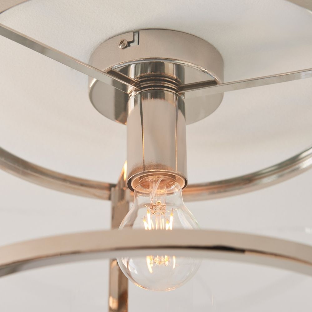 Close up of polished nickel ceiling light with clear glass shade highlighting exposed Edison style filament bulb.