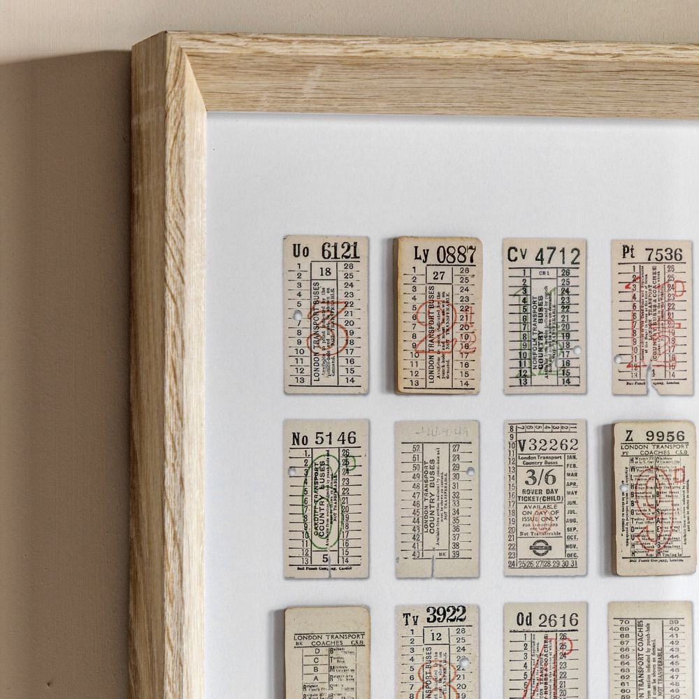 Close-up detail of framed vintage ticket collage artwork with retro transport tickets and light oak-effect frame.