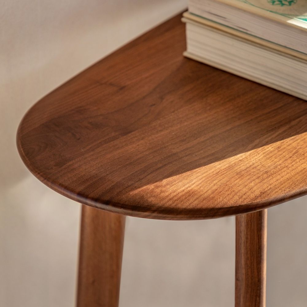 Detailed close up of the rounded boat shaped edge on a walnut console table showing rich wood grain and smooth finish.