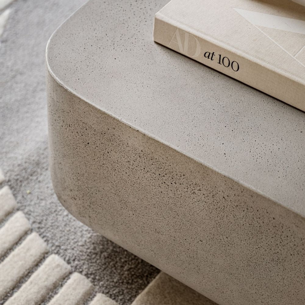 Close up of concrete effect coffee table surface showing subtle texture and rounded corner detail with book on top.