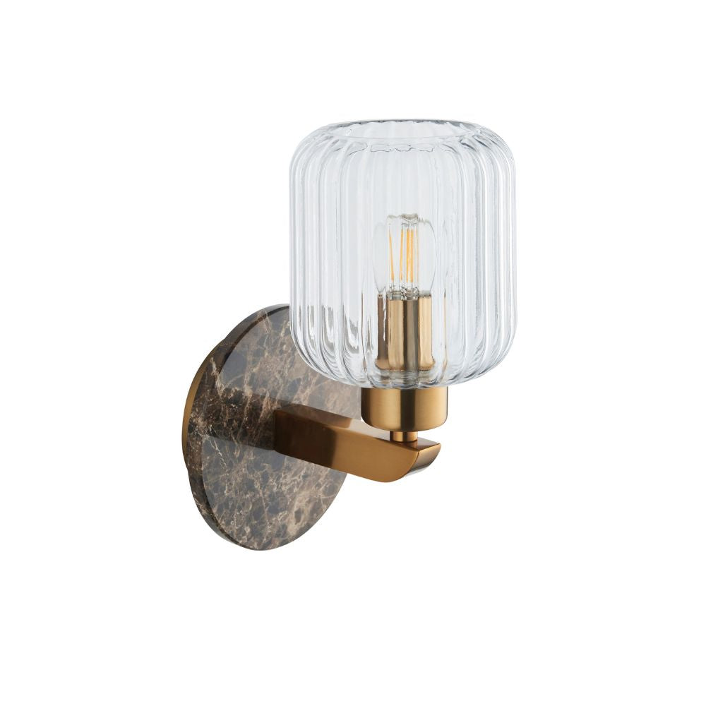 Contemporary brass wall sconce featuring a ribbed clear glass shade and elegant dark marble-effect circular backplate.