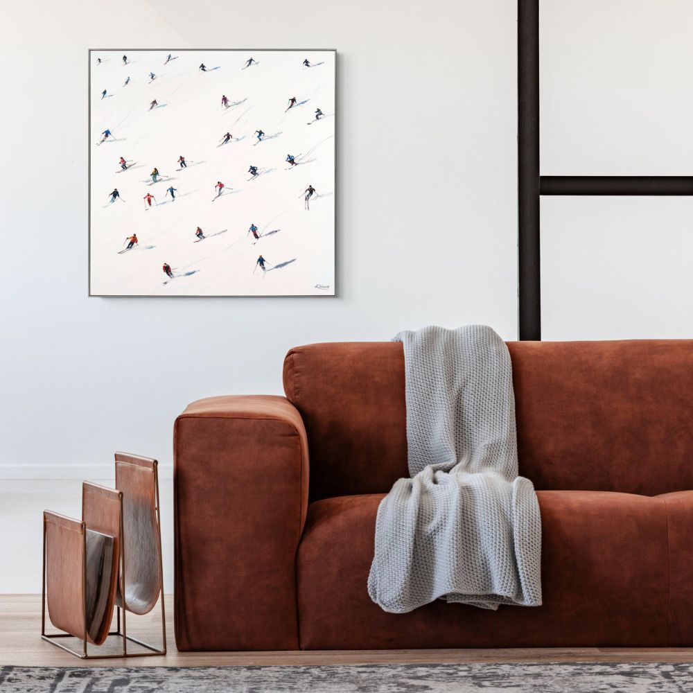 Contemporary skiing artwork displayed above a brown leather sofa in a modern living room setting.