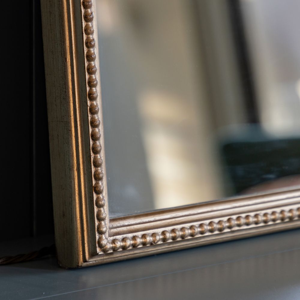 Detailed corner close-up of an antique gold wall mirror frame with ornate beaded edging and aged finish.
