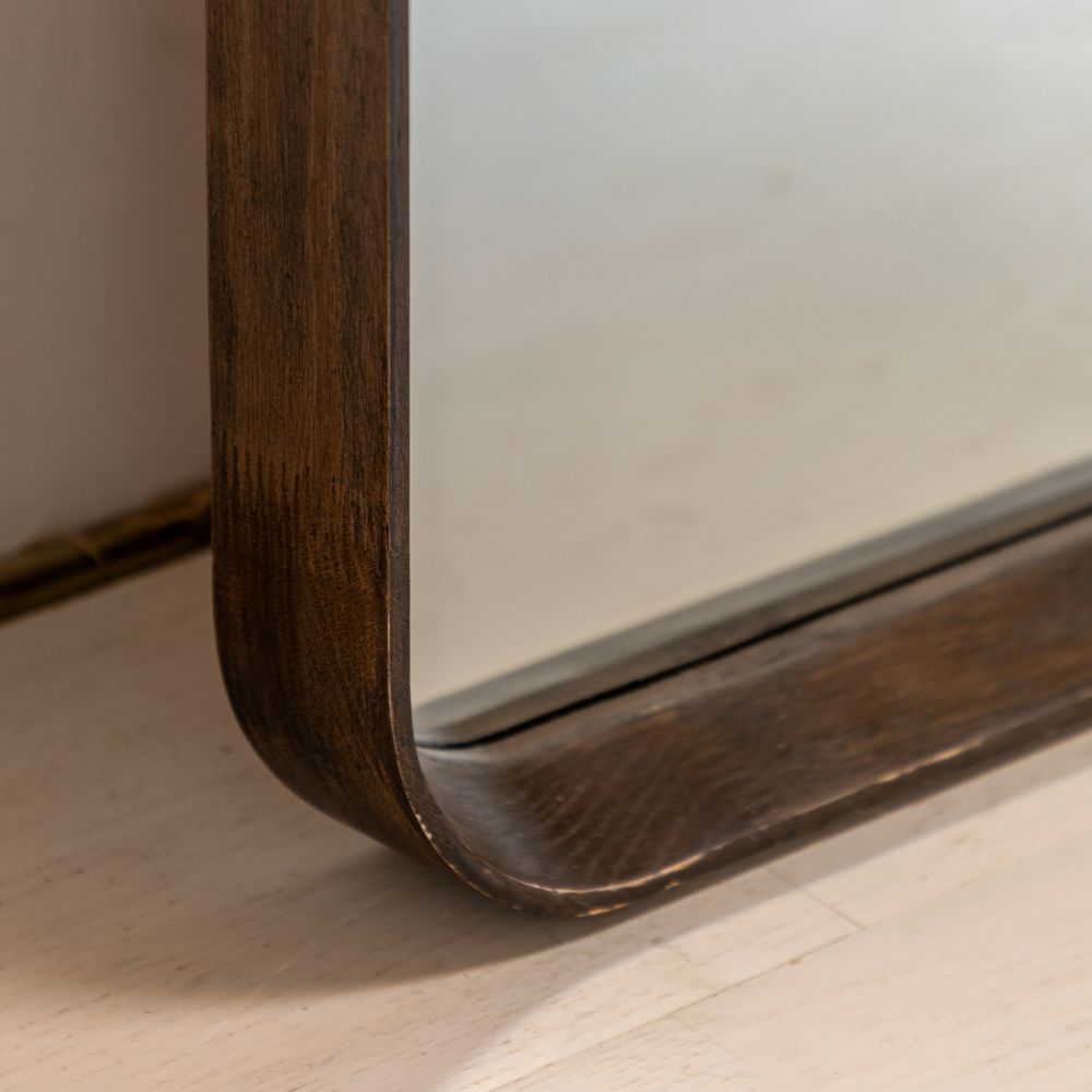 Detailed corner close-up of a dark wood full length mirror frame with rounded edges and rich natural wood grain.