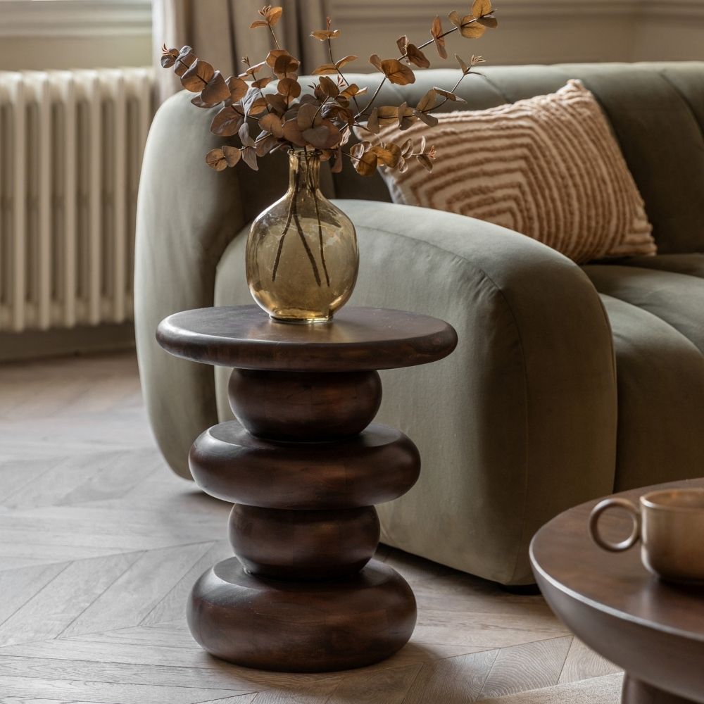 Dark mango wood retro side table styled in a modern living room beside a sofa with decorative vase on top.