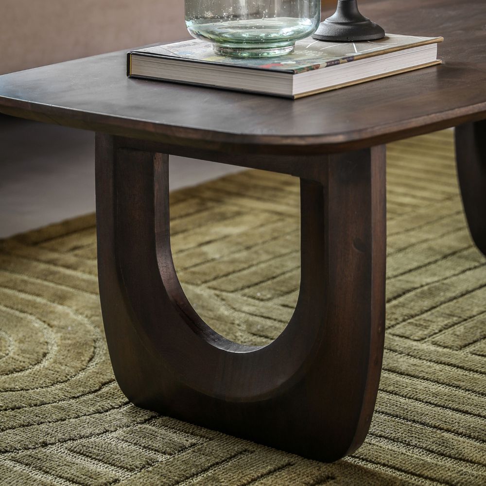 Close up of carved U-shaped leg showcasing rich dark mango wood grain and smooth sculptural form.
