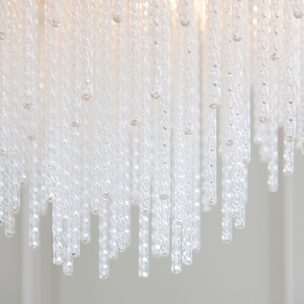 Close up of cascading glass rods on a brass pendant light showing intricate textures and layered design.