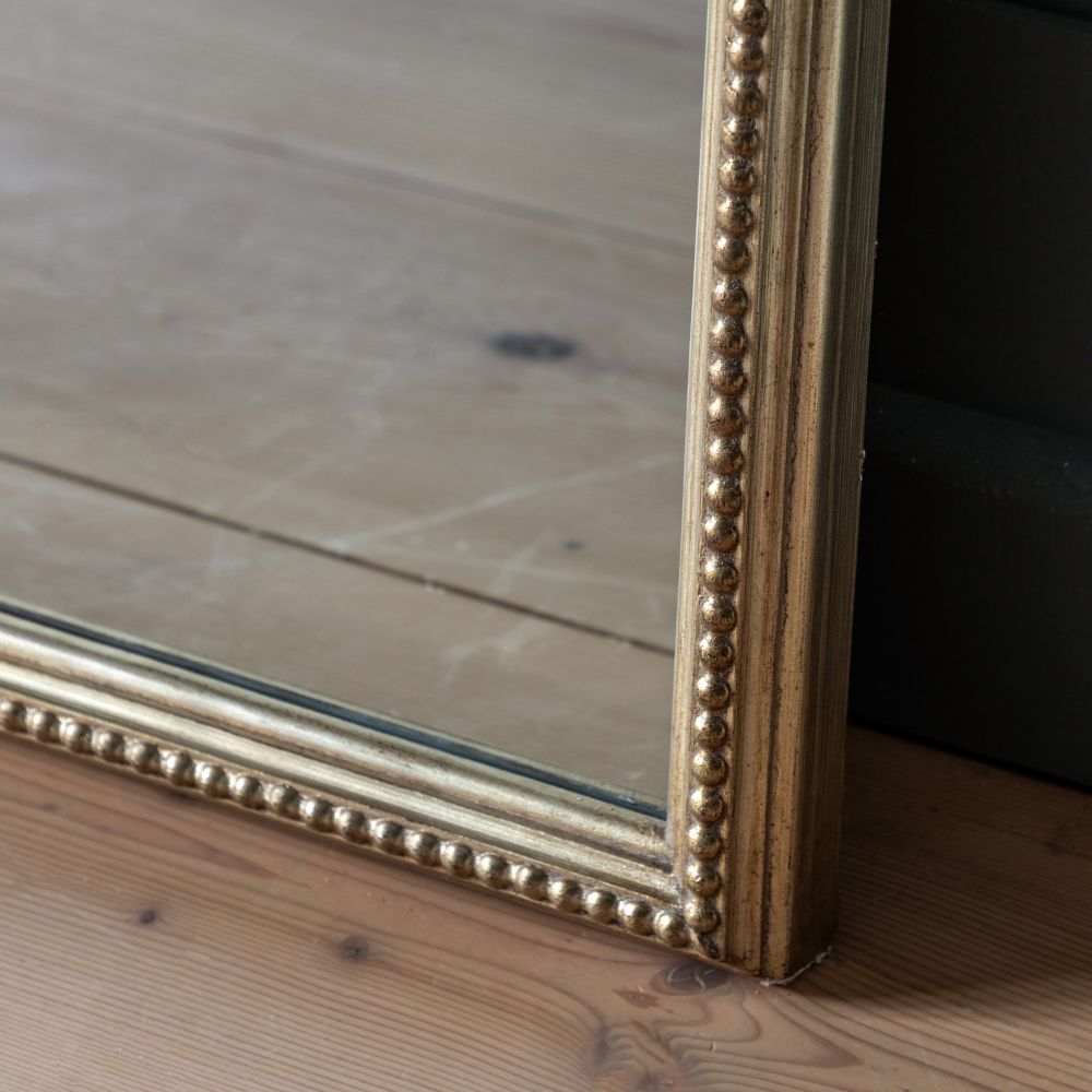 Detailed corner close-up of an antique gold full length mirror frame featuring ornate beaded trim and aged metallic finish.