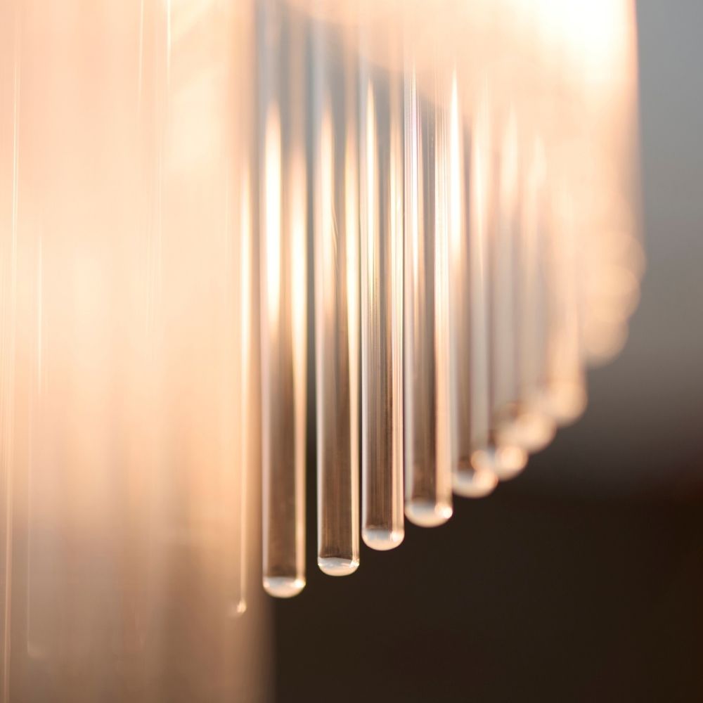 Detailed macro view of glass rods diffusing warm light on a brass tiered ceiling light.