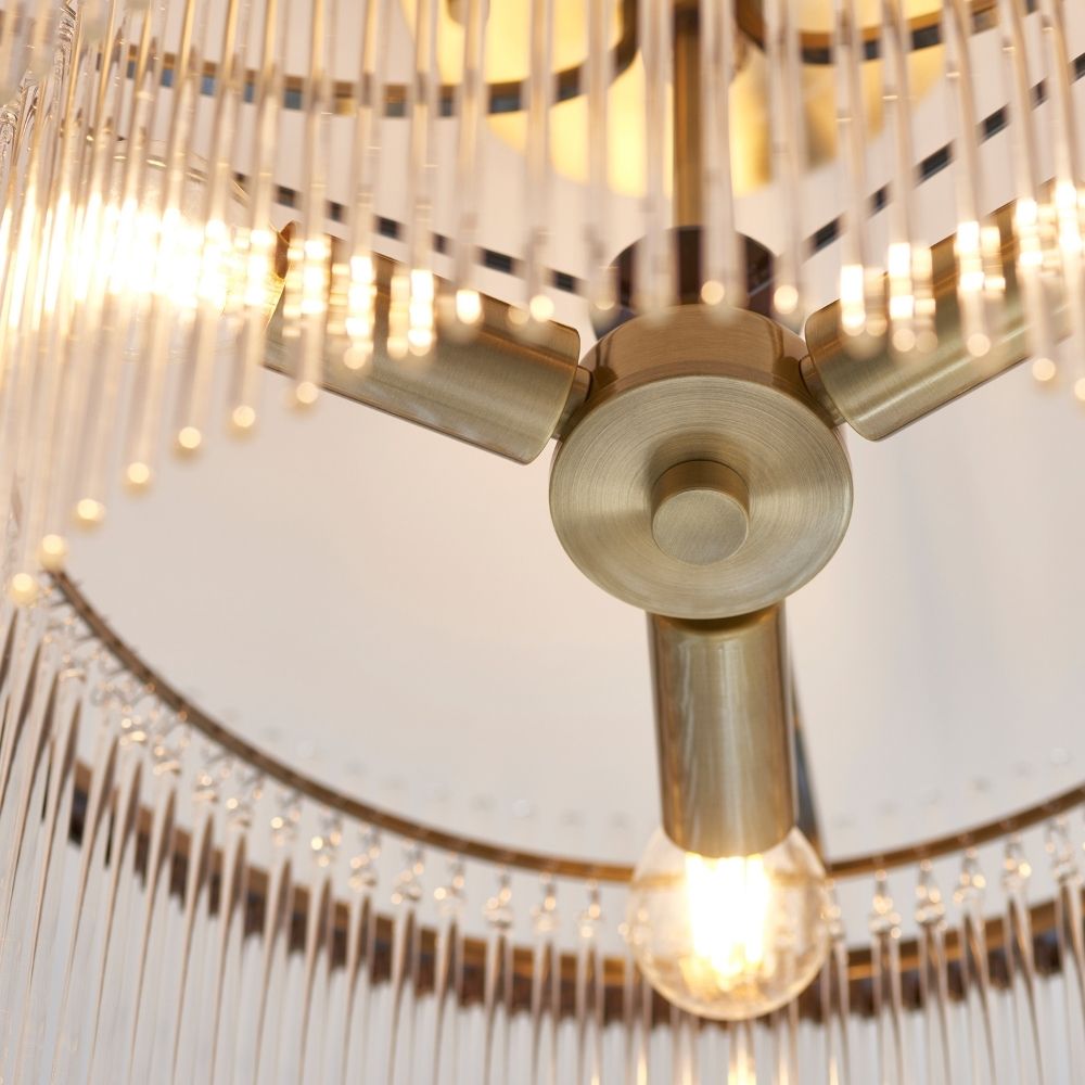 Detailed underside view of antique brass ceiling light with exposed bulb and surrounding clear glass rods creating a decorative effect.
