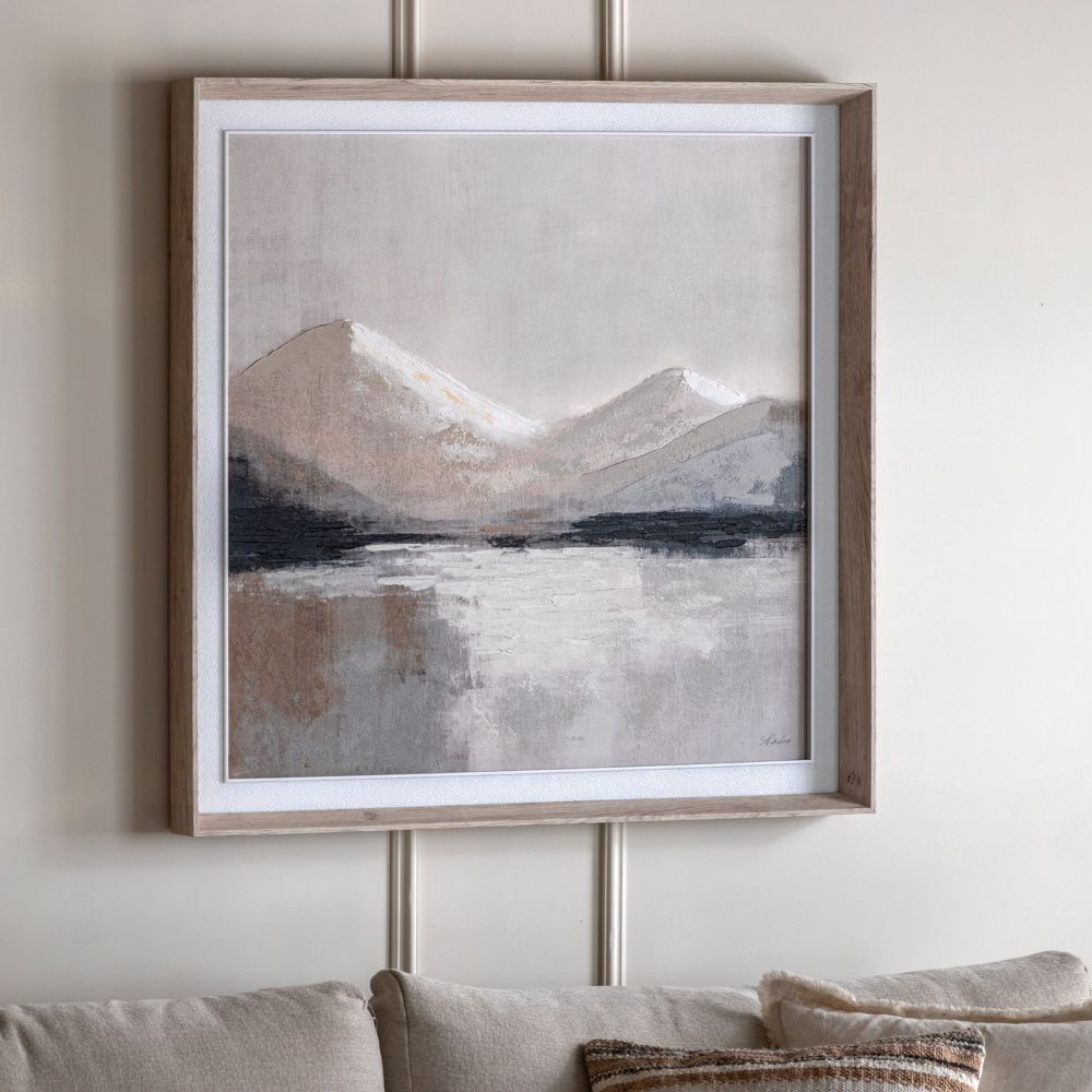 Framed abstract mountain landscape canvas wall art in neutral beige, grey and black tones displayed above a sofa.