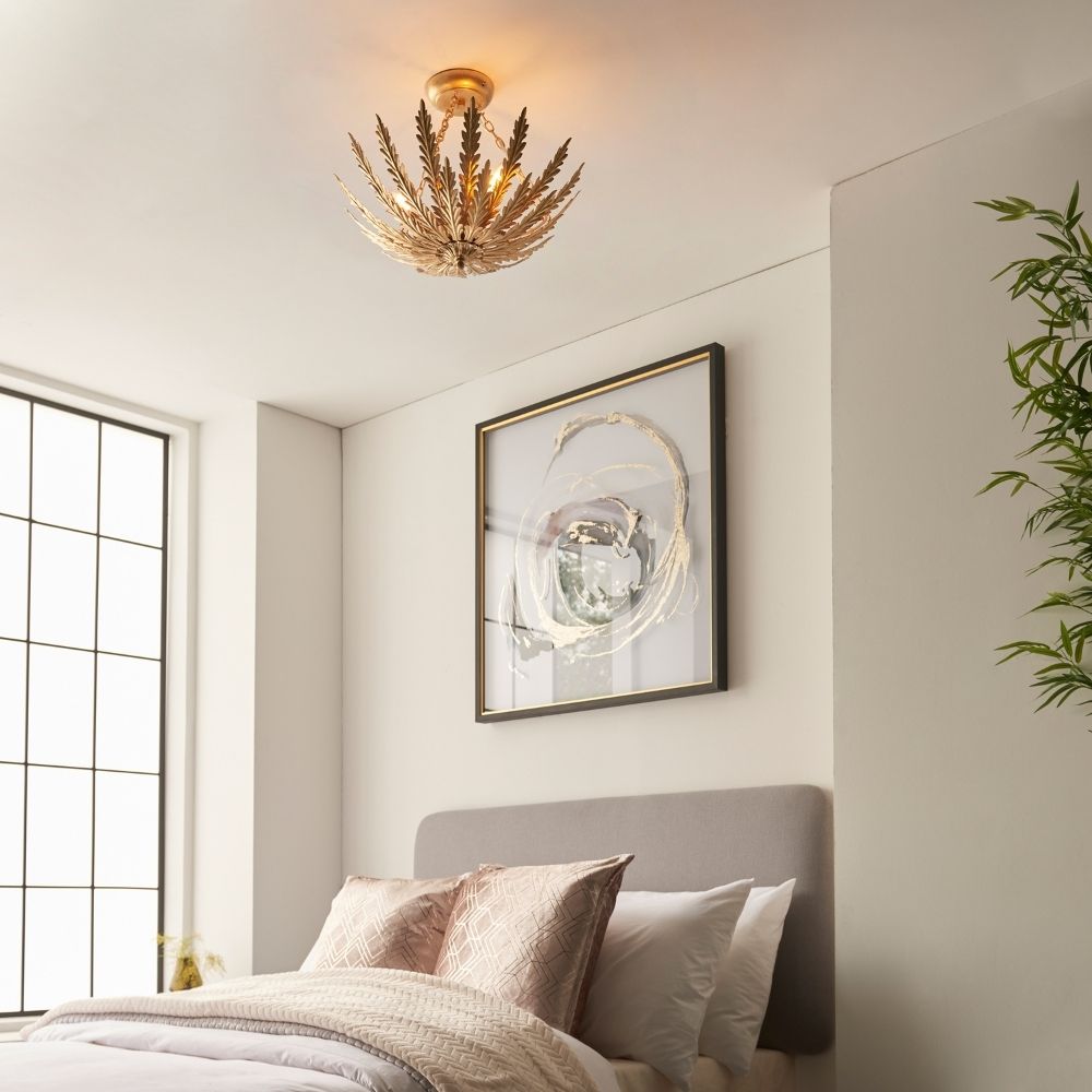 Gold leaf semi flush ceiling light installed in a modern bedroom with neutral decor, wall art and soft furnishings.